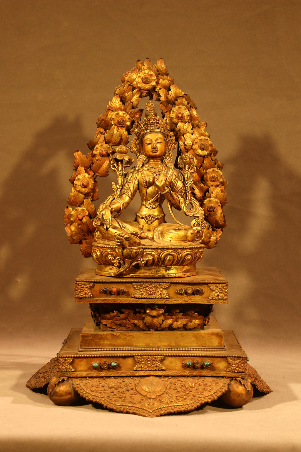 Full frontal view of Green Tara seated on an ornate throne