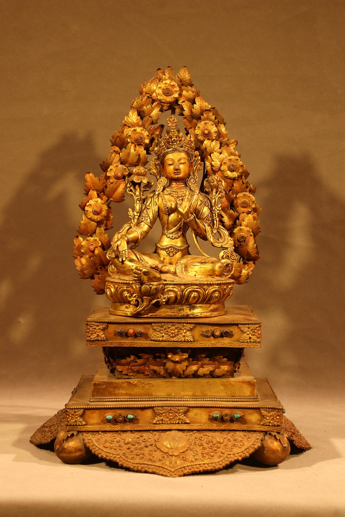 Full frontal view of Green Tara seated on an ornate throne