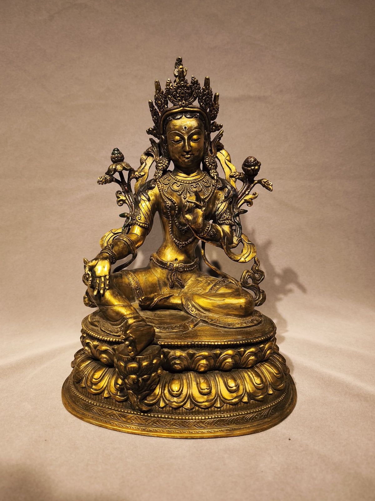 Frontal view of the copper Green Tara on her pedestal.